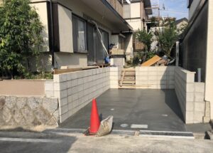 道路沿いの既設の間知石（けんちいし：石積み用に四角すい状に加工された石）は駐車場の間口分を撤去。<br />
外構工事をはじめに行ったことにより、駐車スペースを確保できました。